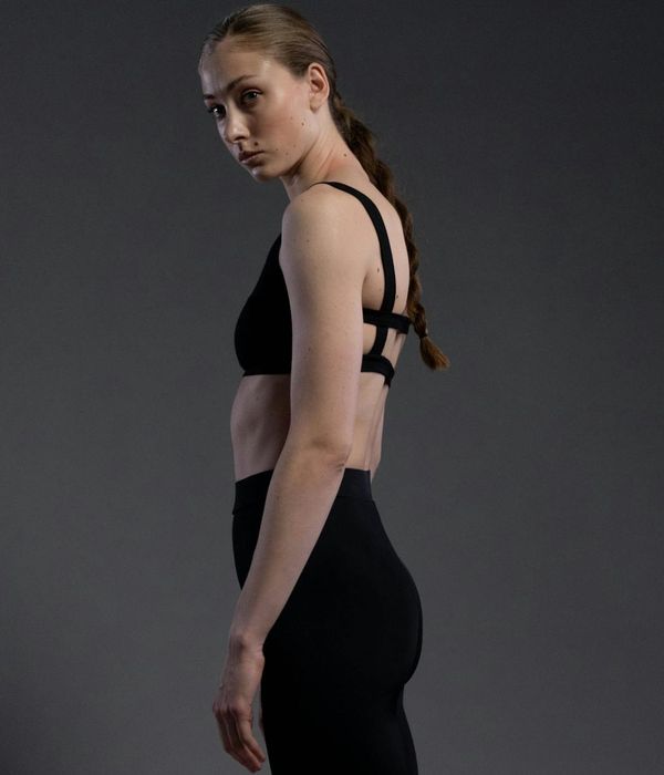 Woman in a calm, focused pose against a dark, minimalist background.